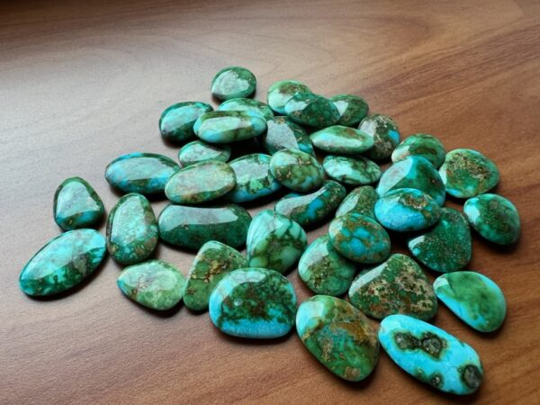 Dark green turquoise stones spread out on a desk