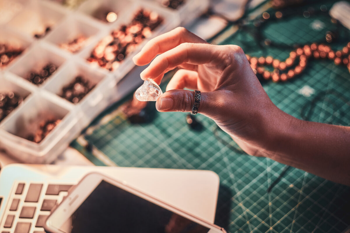 Talented jewelry beads maker is holding crystal clear semi-precious stone in hand.
